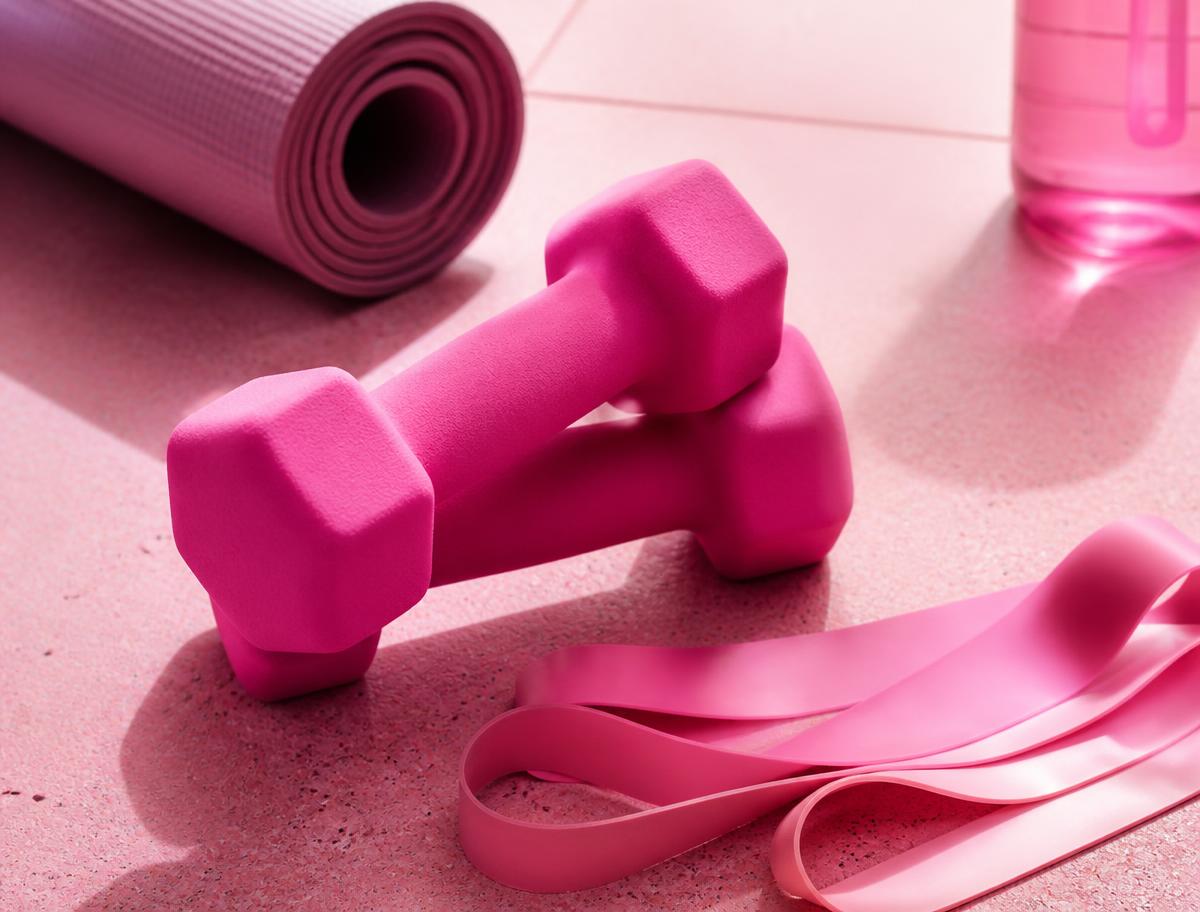 Pink dumbbells and resistance bands in a bright fitness studio